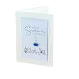 A folded greeting card with a white border and a light blue center panel. The card features the words 'JUST KEEP Swimming' in black script and outline drawings of underwater plants and a small blue fish ornament.