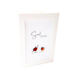 A white greeting card featuring the words 'Soul Sisters' in black script and a small illustration of two glass pebble birds, one holding a flower.