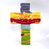 Fused glass cross in rainbow colours, to hang in a window or place in wooden stand