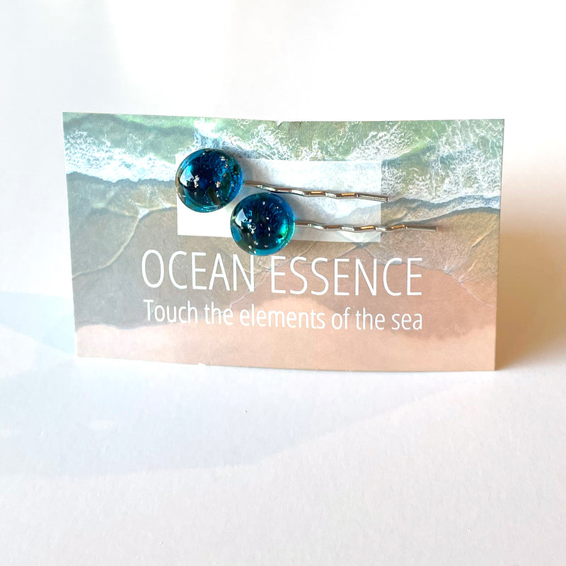 Hair pin close-up: glass encloses grains of visible beach sand